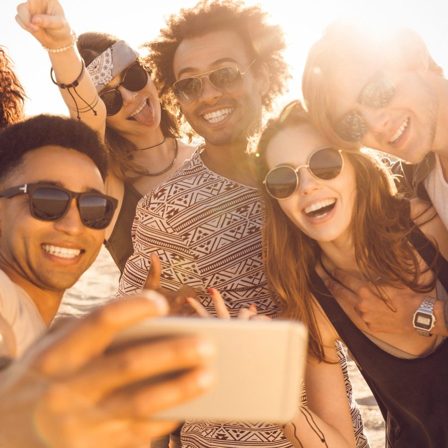 Group of multiracial happy friends taking selfie and having fun on a beach